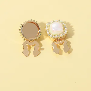 Macro detail of gold collar clips featuring iridescent shell stone and pearl accents