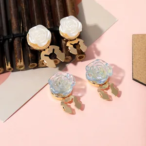 Detail of rose-shaped magnetic clips in ivory white and gradient blue with gold bases
