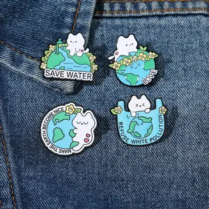 Détail de quatre épingles en émail chat écolo avec strass sur tissu en jean bleu