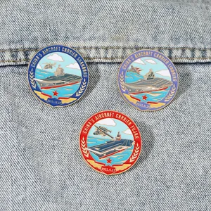 Detailed close-up of three aircraft carrier enamel pins on a blue denim background