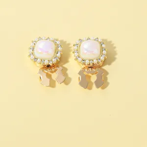 Macro detail of gold vintage square ear clips with lavender tiles and pearl trim