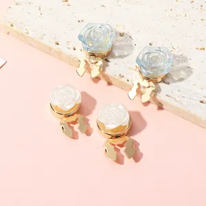 Detailed view of rose flower scarf buckles in light blue and pearl white with gold bases