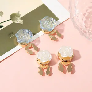 Macro shot of rose flower clips in light blue and cream white with golden metal base