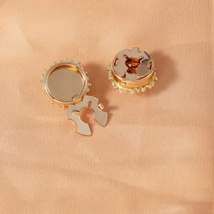Elegant gold metal collar buttons with pearl accents on luxury beige silk fabric background