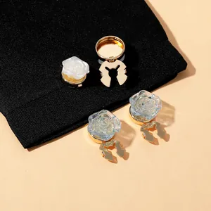 Detail view of 3D rose pins in white and blue on black fabric with gold metal base