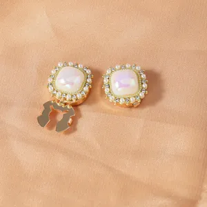 Detail of vintage gold-plated collar clips with square iridescent stone and faux pearls
