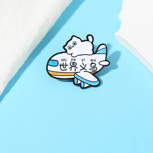 Detail of cartoon white cat enamel pin with a blue airplane and World Yiwu text