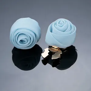 Detailansicht hellblauer Stoffrosen-Clips mit Chiffon-Textur und goldenen Metallklammern