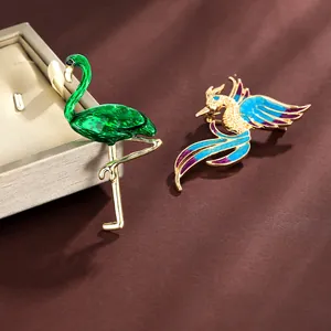 Dettaglio delle spille smaltate a forma di fenicottero e fenice con placcatura oro
