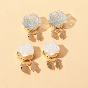 Macro view of rose-shaped collar clips in pearl white and light blue resin with gold base