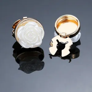 Macro detail showing white resin rose brooch with golden alloy clasp on a black background