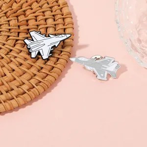 Detailed close-up of two fighter jet enamel pins with butterfly clutch on a woven mat
