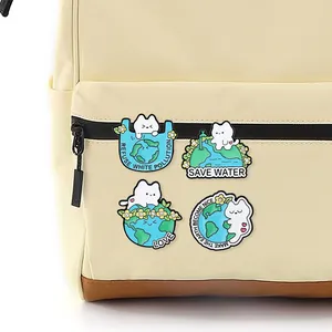 Détail de quatre épingles en émail chat et terre sur un sac à dos en toile beige