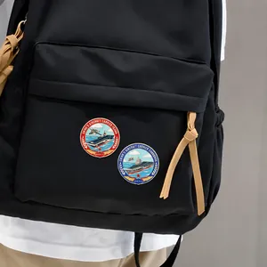 Cartoon aircraft carrier Fujian and Shandong enamel pins displayed on a black canvas backpack