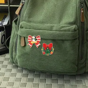 Set di spille smaltate natalizie con pinguino e ghirlanda su uno zaino verde