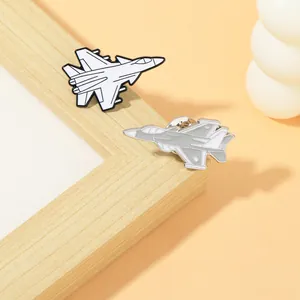Detailed pair of fighter jet enamel pins in white and grey colors on a wooden stand
