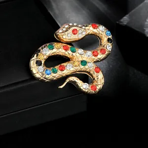 Dettaglio macro della spilla a serpente dorata con strass colorati e squame fini