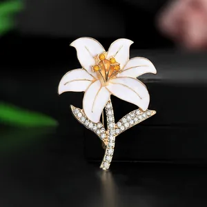 Macro detail of lily flower brooch with white enamel petals and golden rhinestone stem