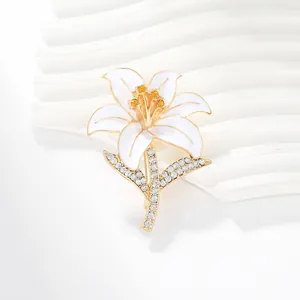 Detail of elegant white enamel lily brooch with gold edges and sparkling crystals