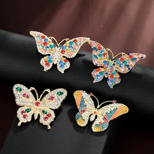 Detailed macro of four golden alloy butterfly brooches with colorful rhinestones and enamel