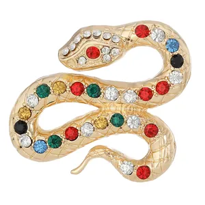 Spilla a serpente dorata con strass colorati e finitura testurizzata su sfondo bianco