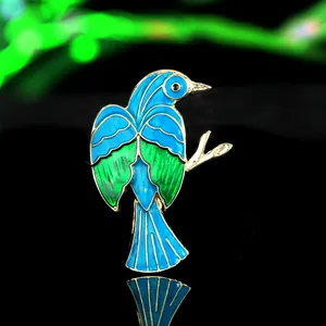 Dettaglio macro di spilla a uccello in smalto blu e placcatura oro su superficie lucida