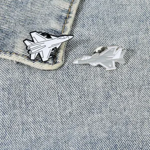 Detailed close-up of airplane enamel pins on blue denim fabric showing metal textures