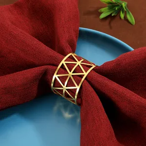 Close-up of golden geometric triangle metal napkin ring on a dark red linen cloth