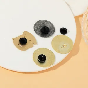 Dettaglio del retro di quattro spille in lega con finiture in metallo oro e argento