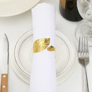 Macro detail of gold leaf napkin ring with intricate vein patterns on a white dinner plate