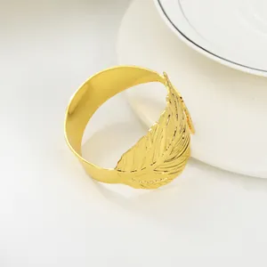 Elegant gold feather open bracelet with detailed texture shown on a minimalist white surface