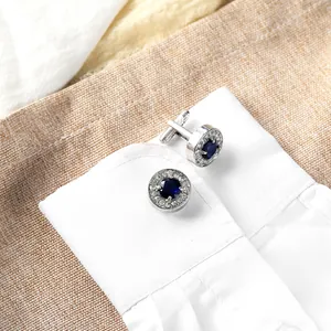 Detailed close-up of premium round silver cufflinks with blue zircon on a white shirt cuff