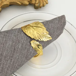 Close-up of golden metal leaf napkin ring on a grey linen napkin and white porcelain plate