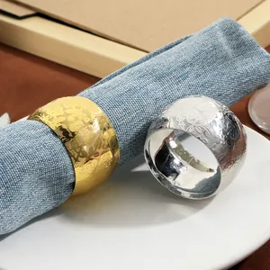 Elegant gold and silver napkin rings with floral embossed texture on blue fabric