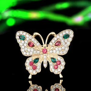 Macro detail of a golden butterfly brooch with multicolored crystals on black mirror