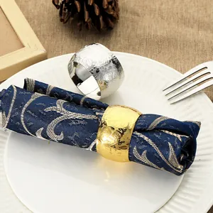 Floral embossed drum napkin rings in gold and silver finish on elegant navy fabric