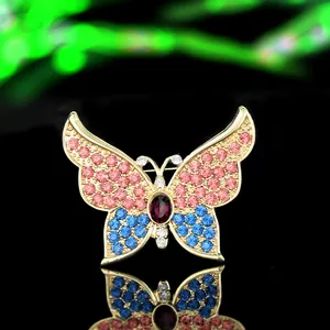 Detailed close-up of a golden alloy butterfly brooch with pink and blue rhinestones