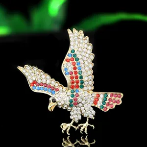 Elegante broche de águila dorada con pedrería de colores en una pose de vuelo