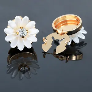 Detailed view of white camellia shirt cufflinks with gold finish and crystal centers