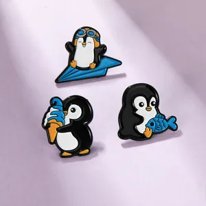 Set di 3 spille in smalto a forma di pinguino con aereo di carta, gelato e pesce