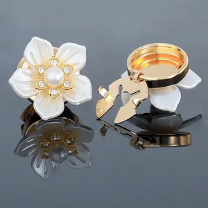 Detail of camellia flower cufflinks with white petals, pearl center and crystal accents