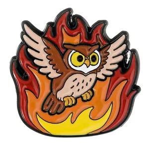 Détail d'un pin's en émail représentant un hibou aux yeux jaunes sur un fond de flammes