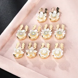 Elegant floral cufflinks with pearls and rhinestones displayed on a pink velvet board