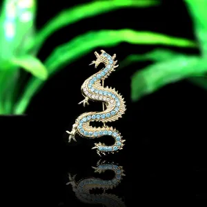 Gothic punk dragon brooch with blue crystals and gold-plated finish on black background