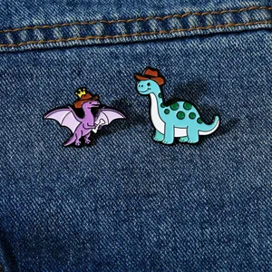 Dettaglio di spille in smalto a forma di dinosauro su denim, con uno pterosauro e un sauropode