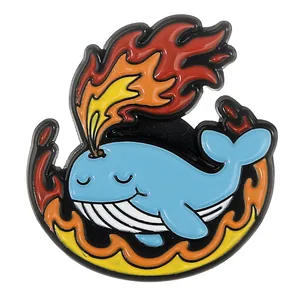 Détail macro d'une broche baleine en émail avec flammes orange sur fond blanc