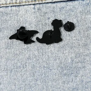 Dettagli del retro delle spille a dinosauro in smalto con chiusure in gomma nera su denim