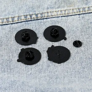 Macro shot of 4 black enamel pin backings with butterfly clutches on denim fabric