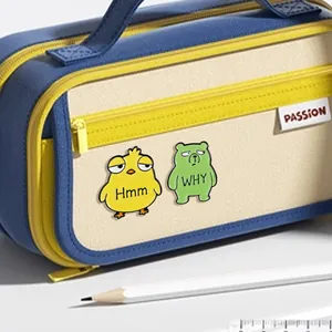 Cute enamel pins with Hmm chick and WHY bear designs pinned on a canvas pencil case