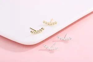 Macro shot of curved S925 silver row diamond stud earrings in gold and silver finish